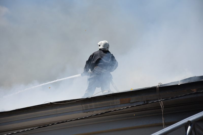пожарный тушит пожар на крыше